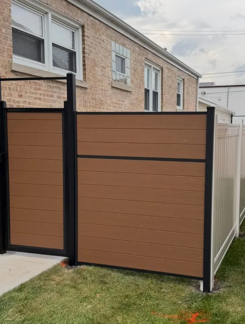 Cedar-brown composite privacy fence with black aluminum posts and a matching walk gate, installed beside a brick Chicago two-flat