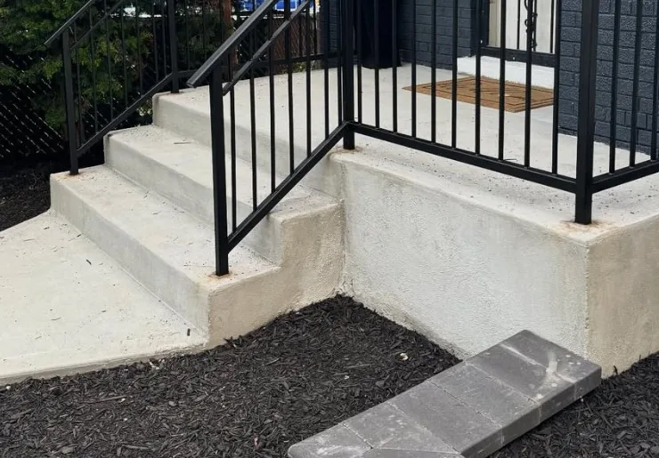 Poured concrete front steps and stoop with a paver set at the base of the walkway