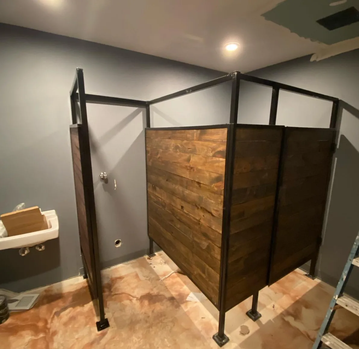 Custom welded steel frames fitted with stained wood plank panels, built as partitions inside a building under renovation